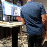 Man working at a Klöud standing desk with an ultrawide monitor