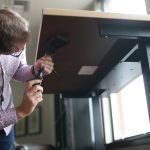 Man adjusting the underside of a Klöud standing desk
