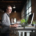 Man working at a Klöud standing desk in a bright office