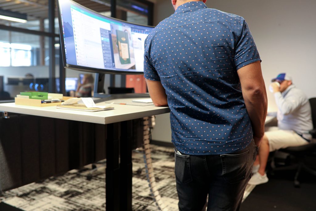 Person standing at a Klöud desk with a curved monitor