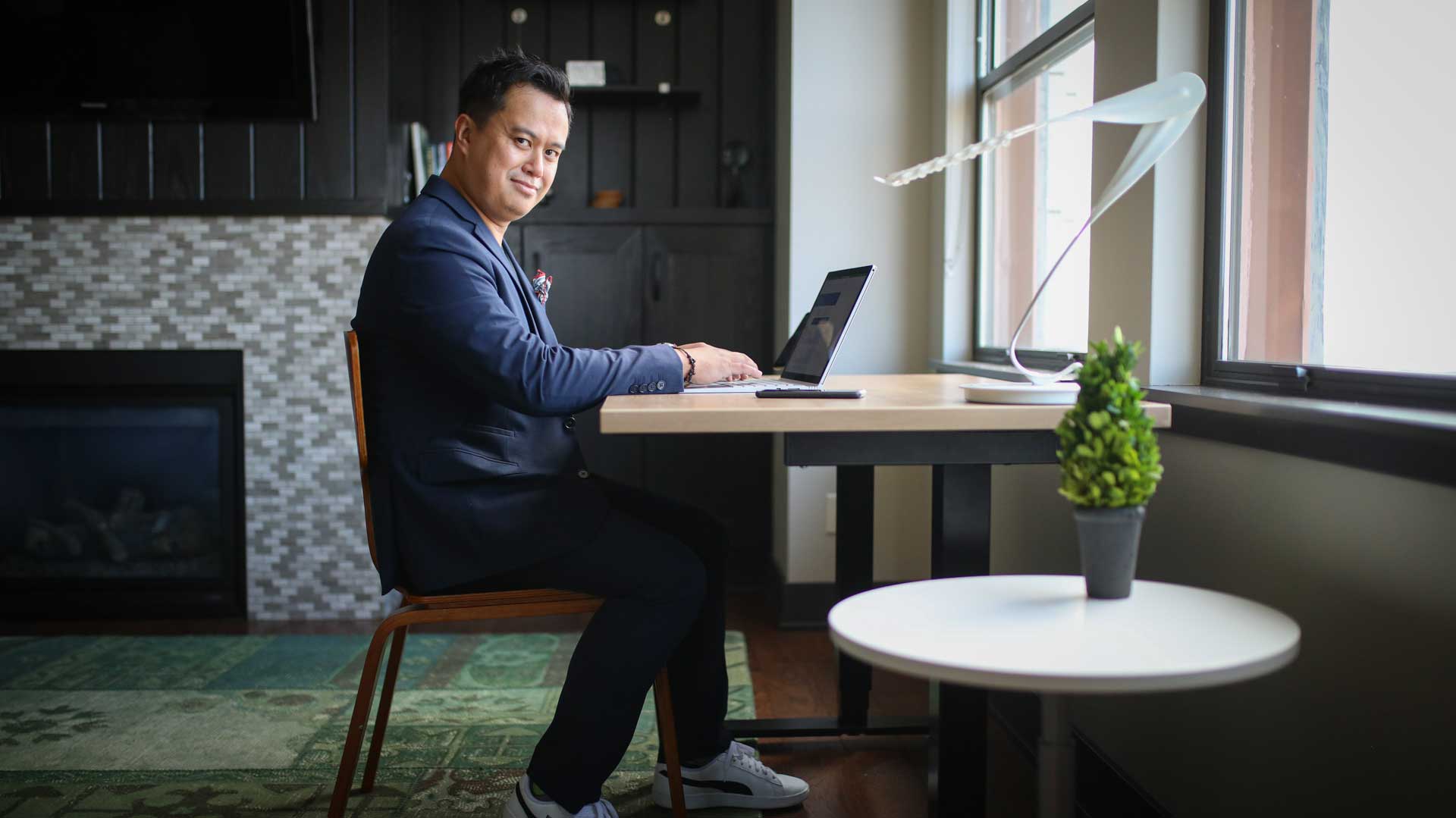 Person seated at a Nimbus standing desk beside a window