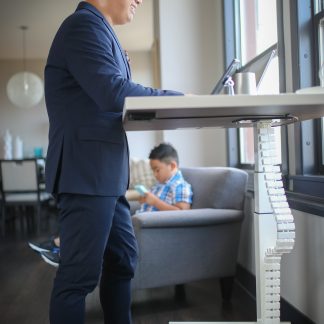 Person working at a white standing desk with the cable-management chain visible