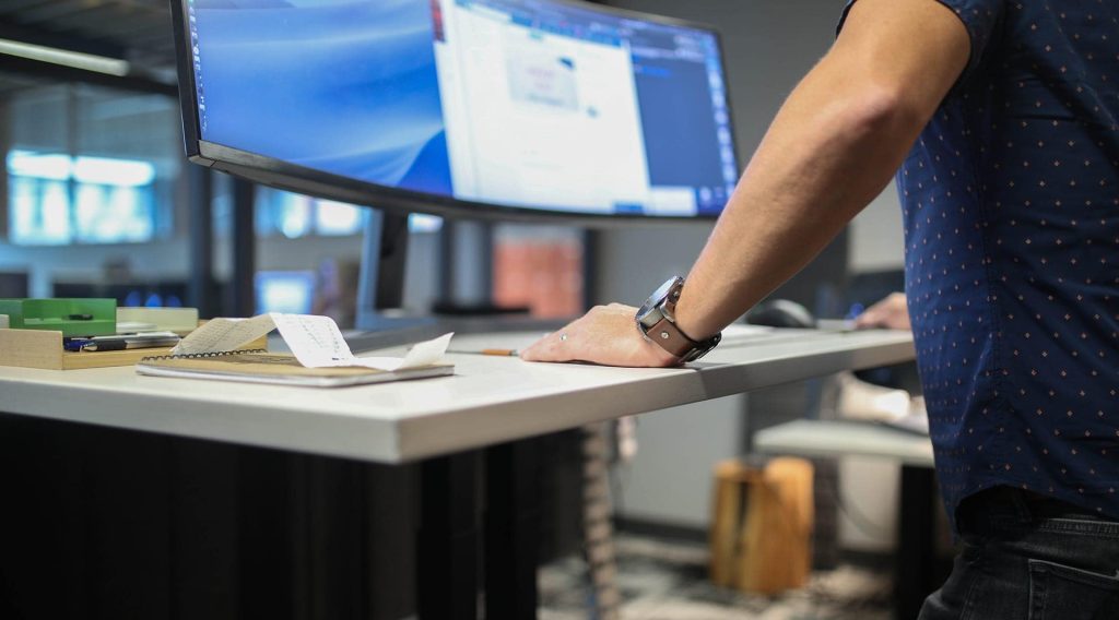 Person using a monitor and white work surface in an office