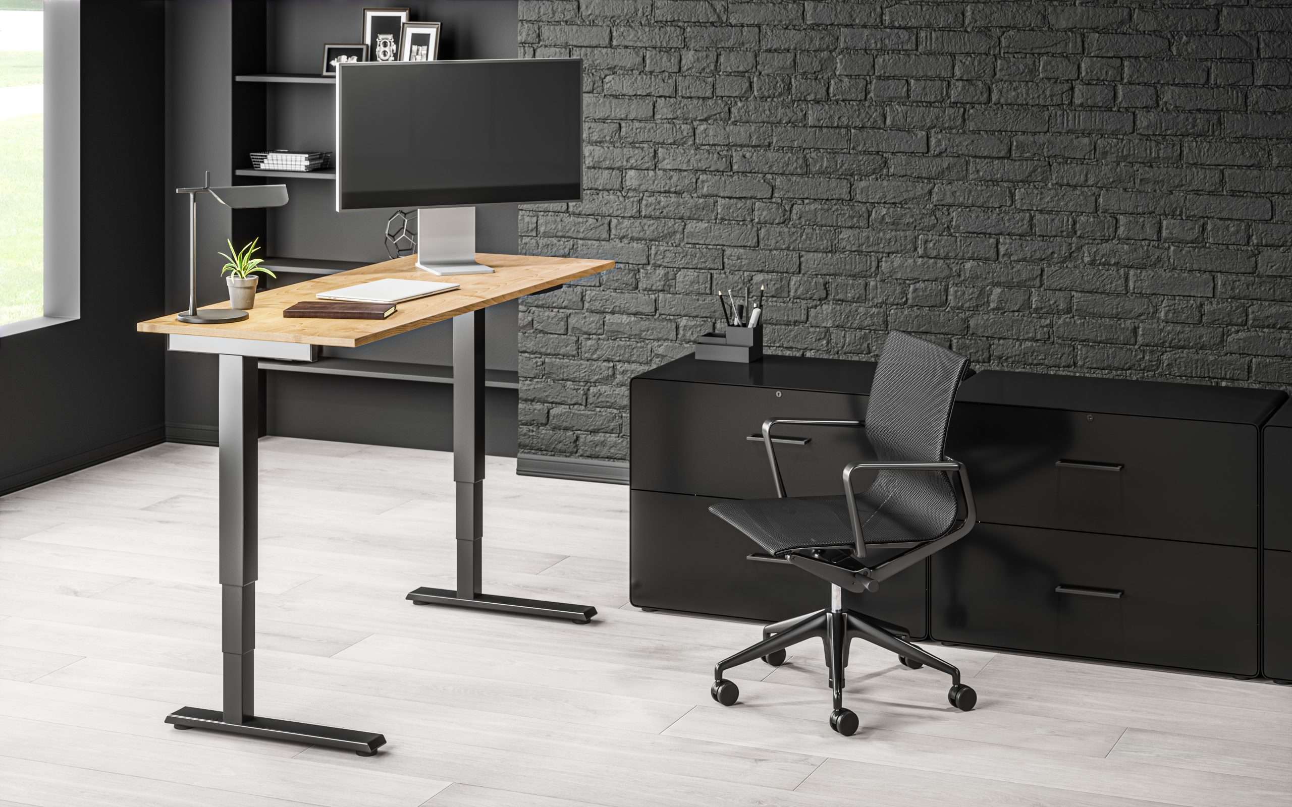 A standing desk with a monitor in a dark home office.